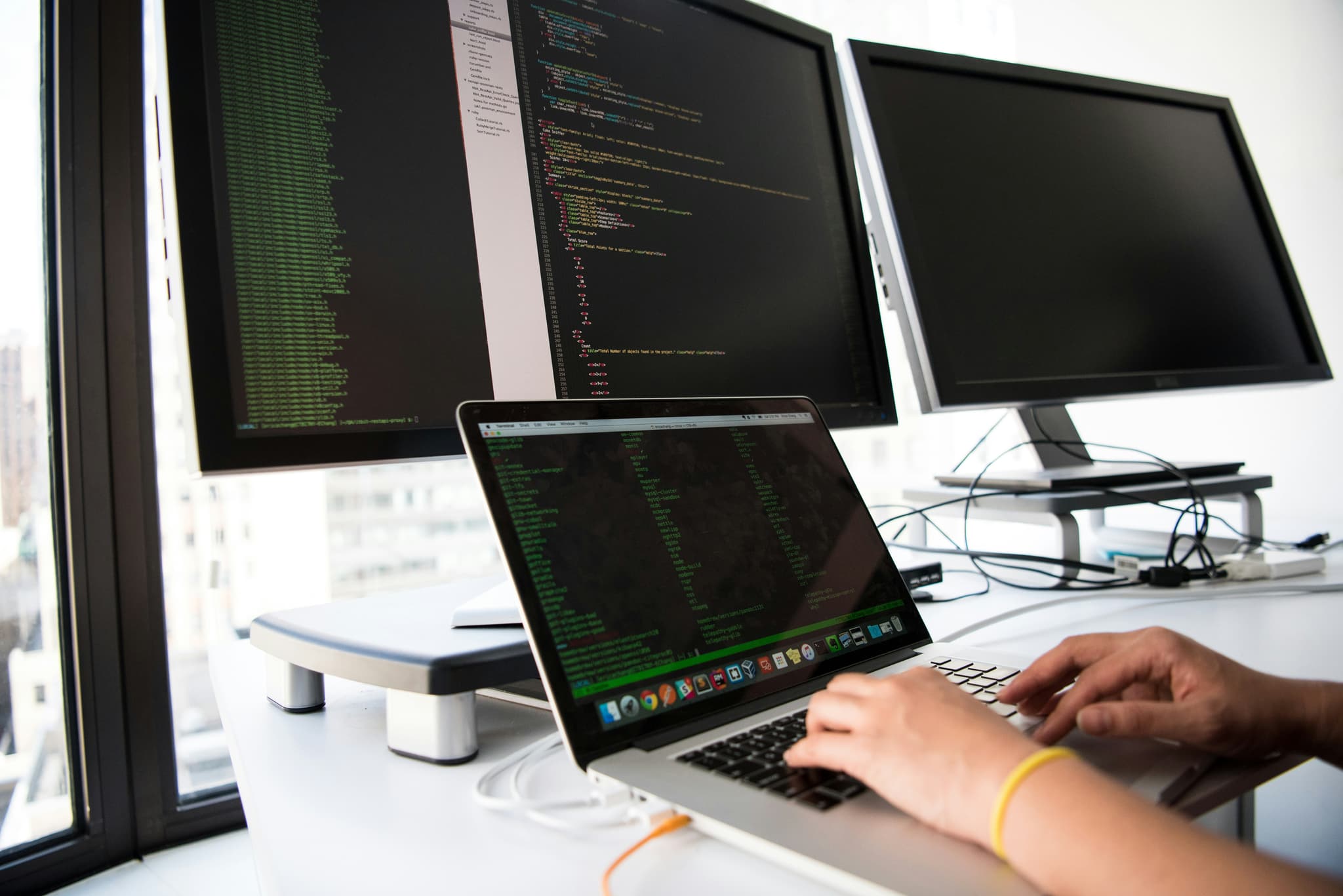 software development engineer coding across triple monitors