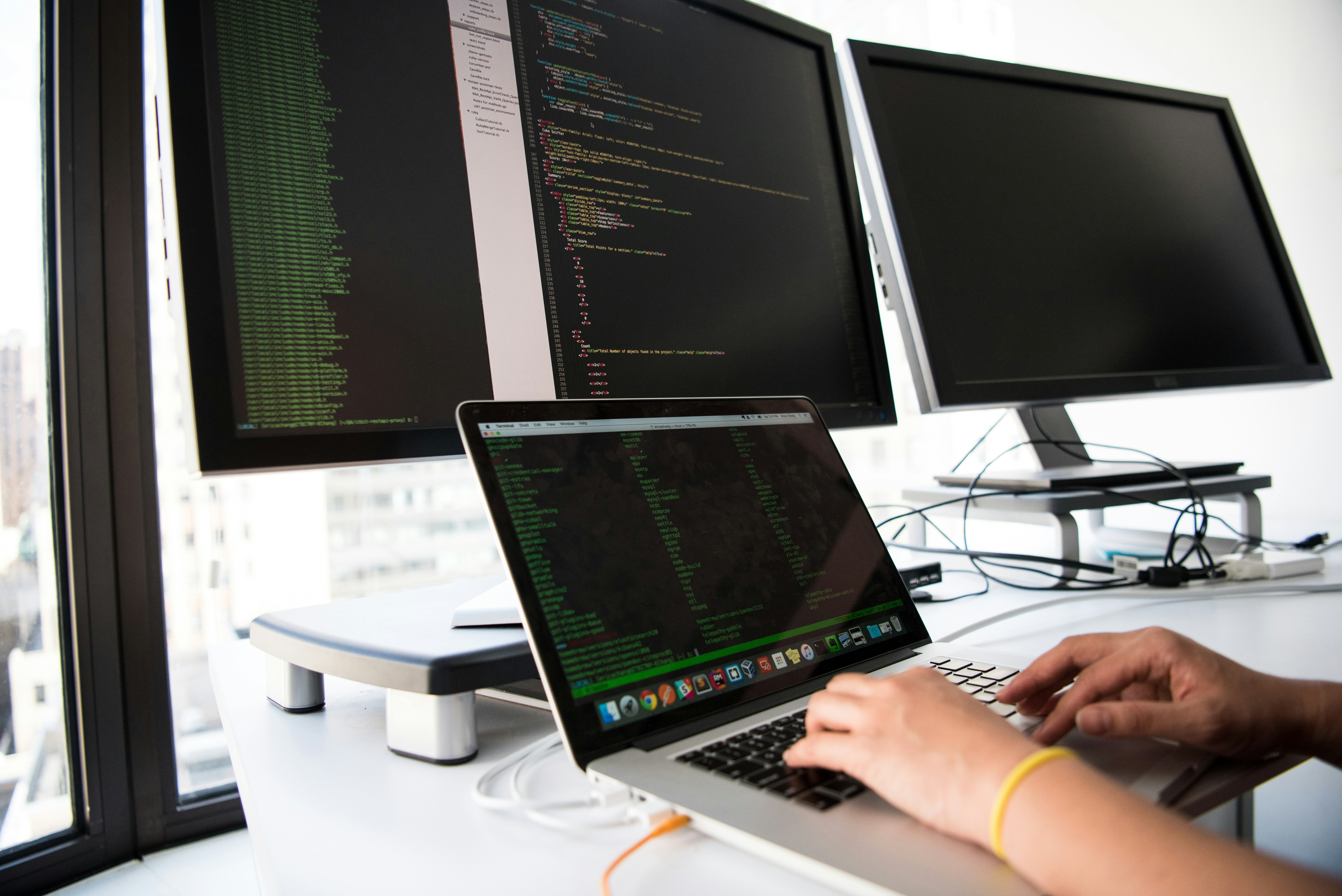 software development engineer coding across triple monitors